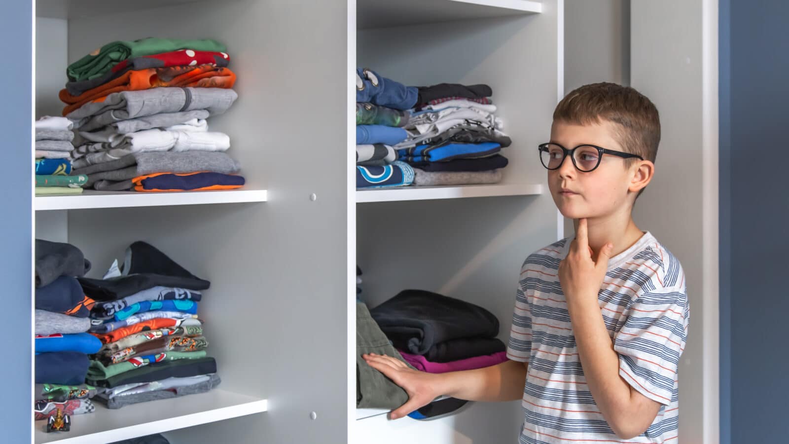 Enfant devant son dressing réfléchissant à sa tenue du jour