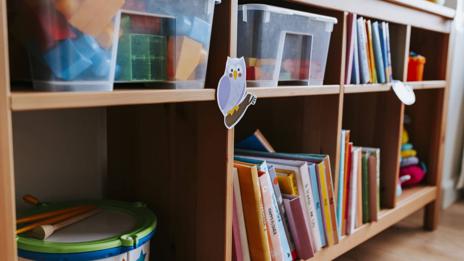 Étagères basses avec bacs de jouets et livres rangés dans une chambre d'enfant