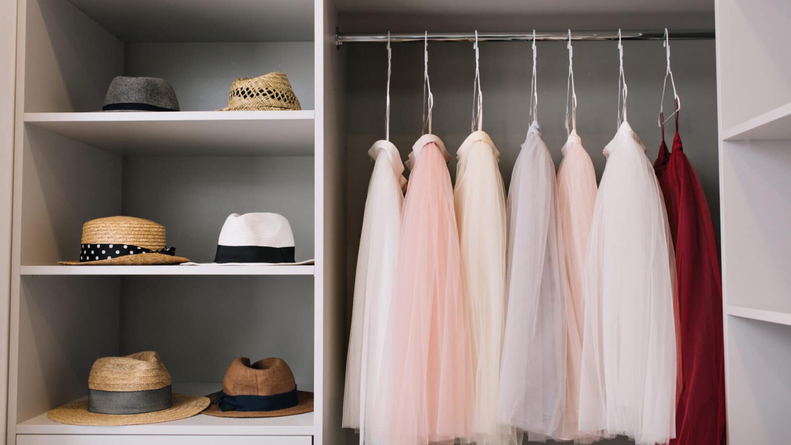 Bright closet with clothes hanging in an organized row and open shelves