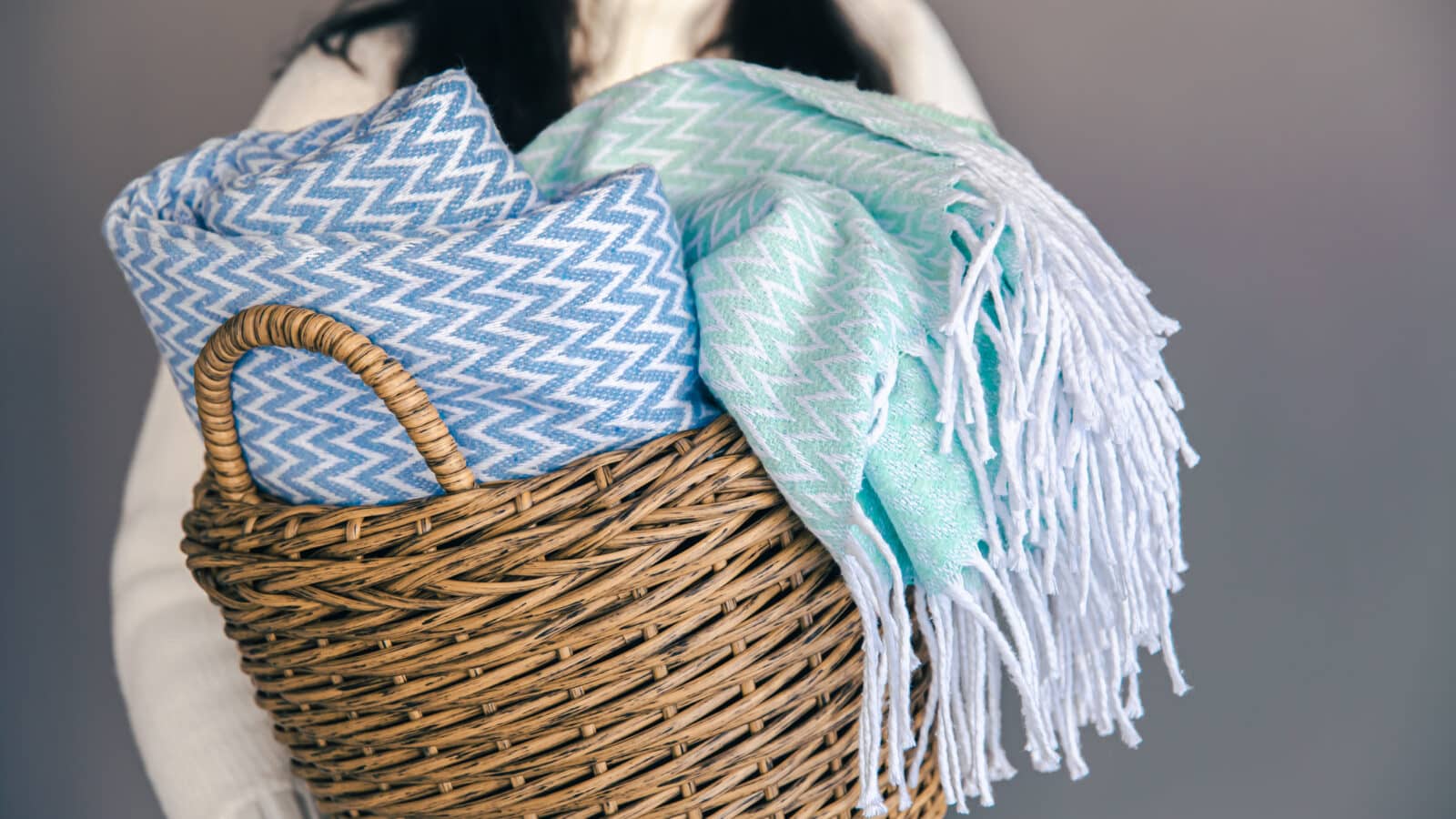 Folded blankets stood on edge in a woven basket, each one visible without unstacking the pile
