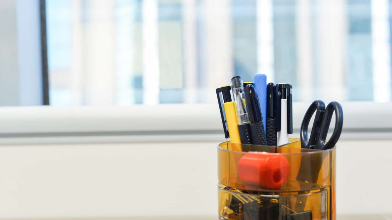 Pot à crayons rempli de stylos et fournitures de bureau triés