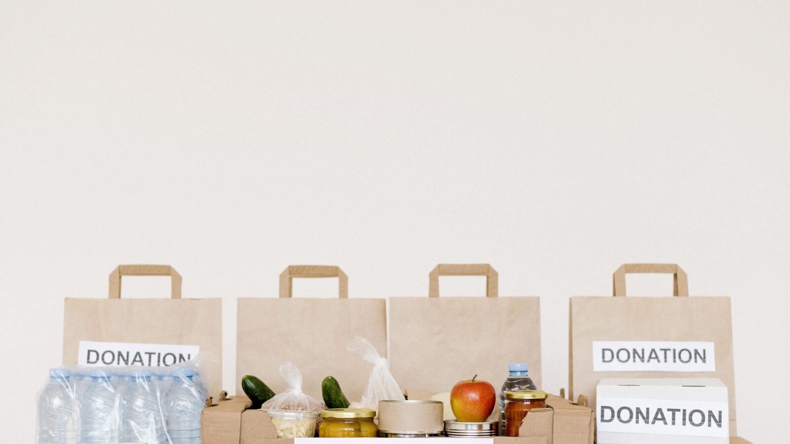 Cartons et sacs de vêtements préparés pour un don, posés au sol avant le dépôt