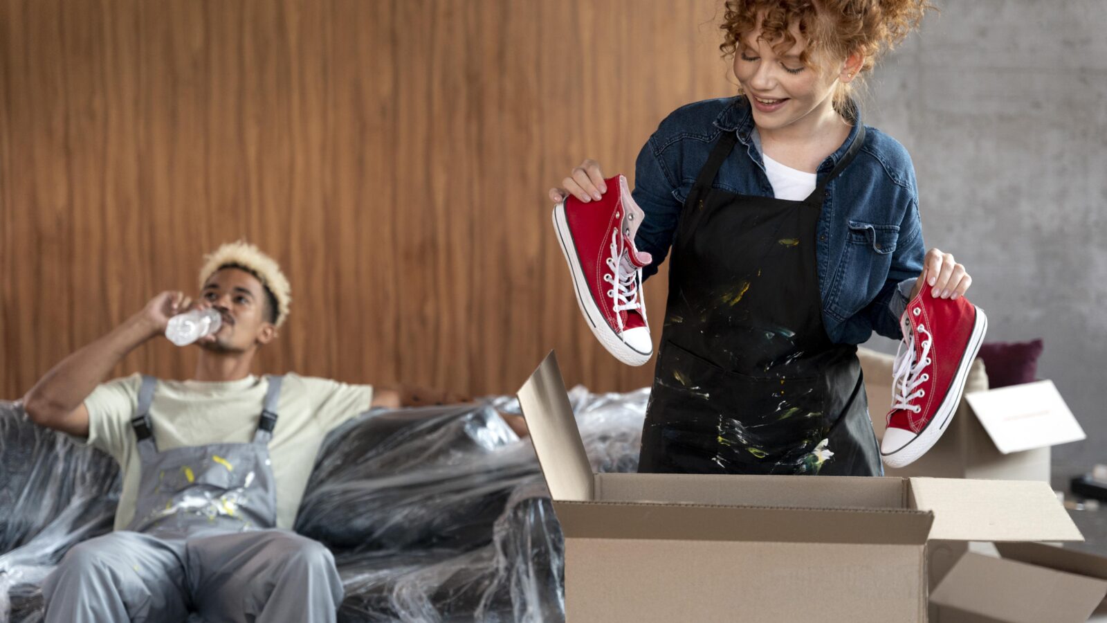 Couple sorting belongings from cardboard boxes while decluttering before a move