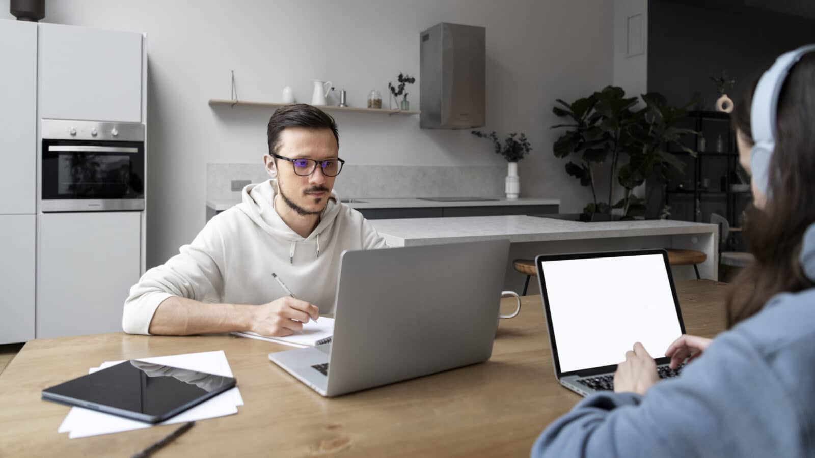 Un homme et une femme partageant le même bureau à la maison, chacun avec son espace de travail