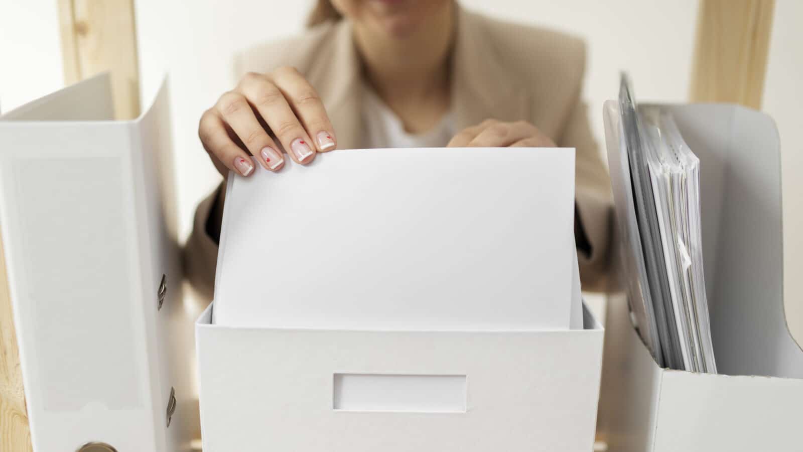 Person sorting a stack of mail and paper documents at an entryway table