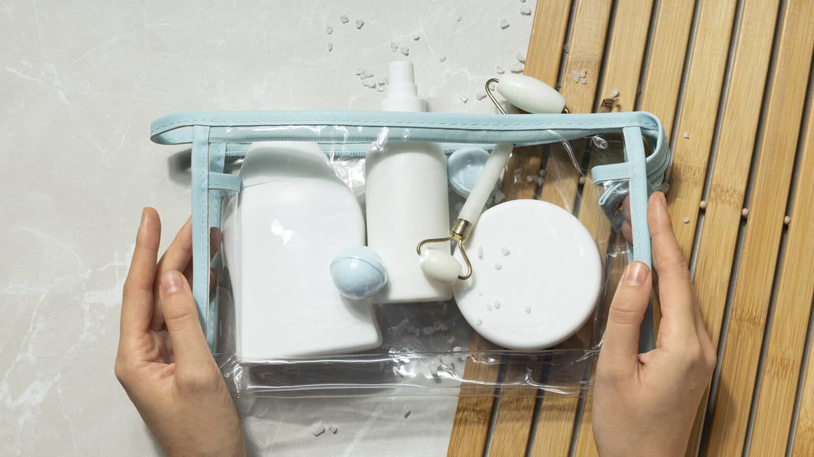 Trousse de maquillage organisée à plat, produits triés par catégorie sur un fond clair