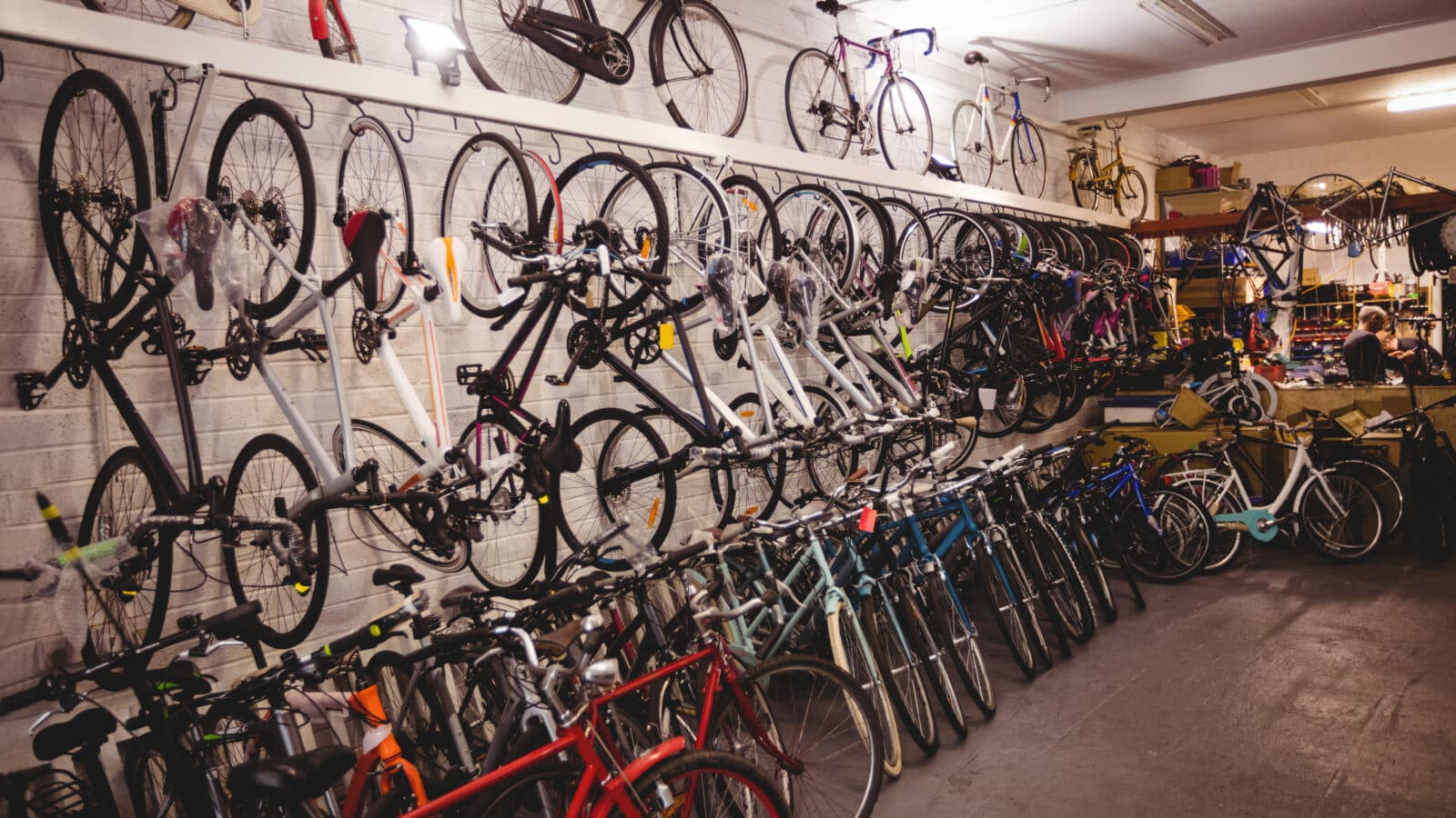 Several bicycles stored side by side against a workshop wall, wheels aligned and floor kept clear