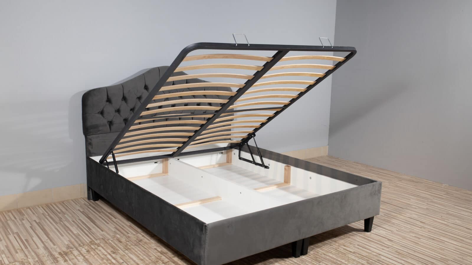 Bed frame with the under-bed storage compartment open, showing empty space for bins