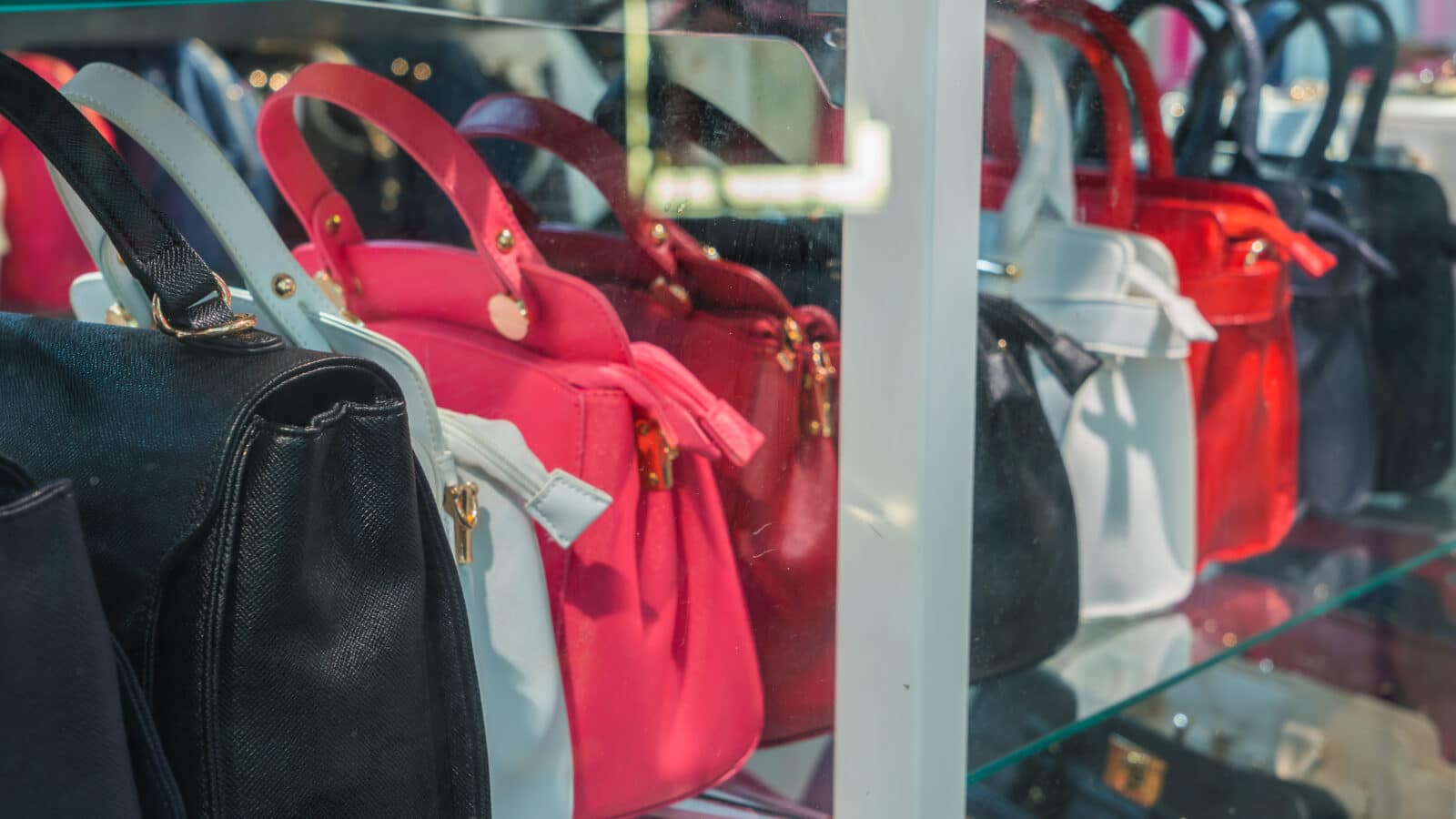 A row of leather handbags standing upright side by side on a shelf, each one keeping its shape