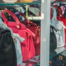 A row of leather handbags standing upright side by side on a shelf, each one keeping its shape