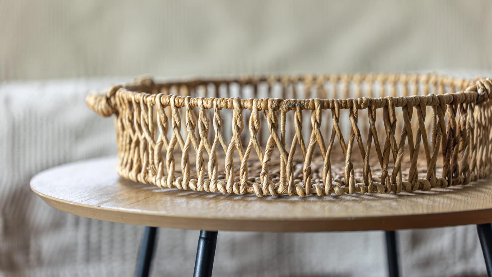 Panier en osier rond posé sur une table basse dans un salon rangé