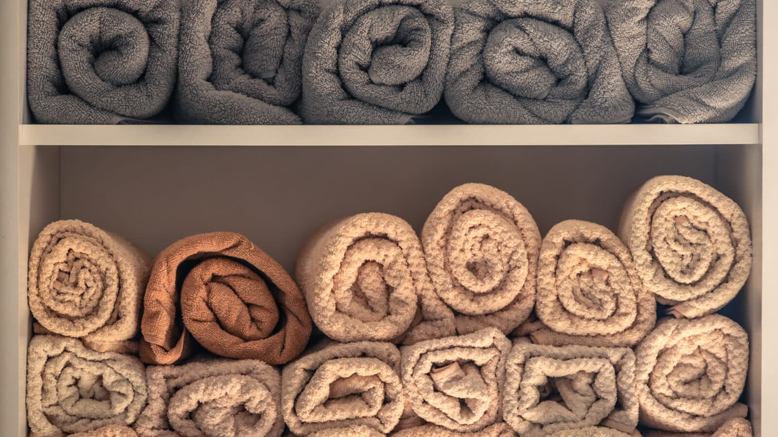 Étagère ouverte avec serviettes de bain pliées et rangées dans une salle de bain