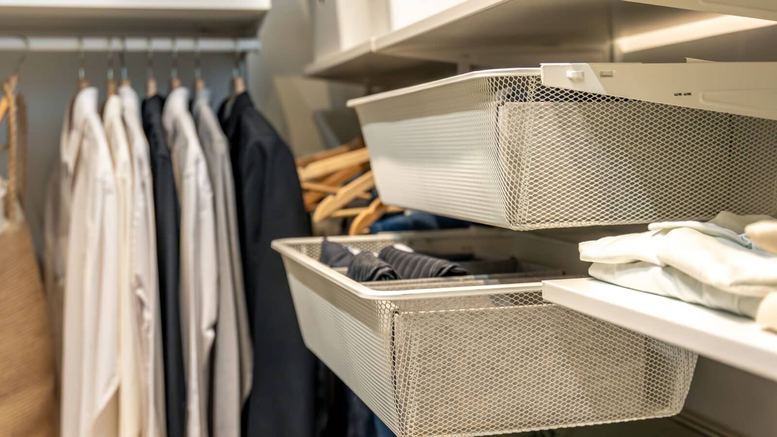 Placard bien organisé avec paniers en filet et vêtements suspendus rangés par ordre