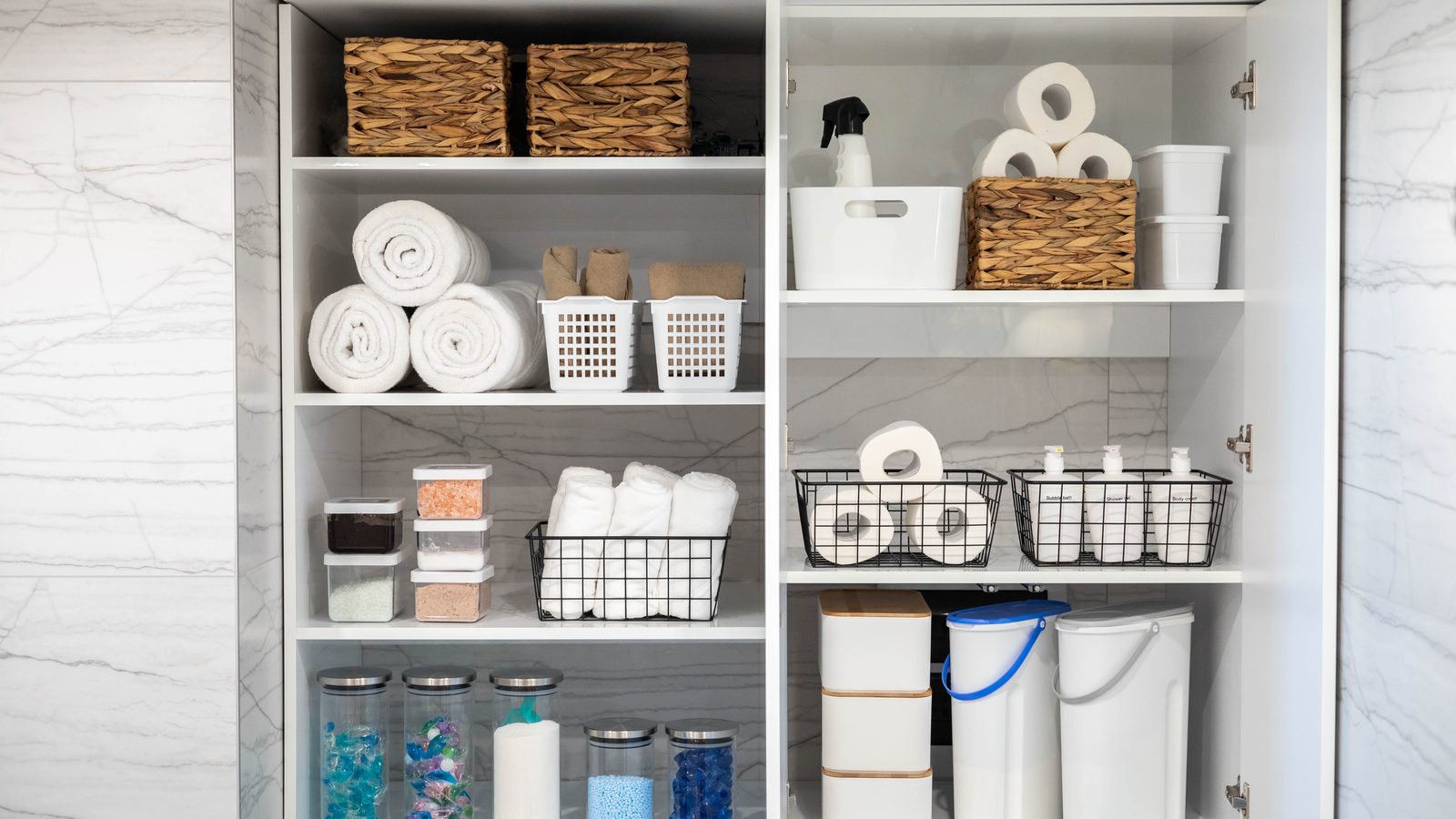 Organized white bathroom shelves with neatly arranged storage baskets and containers