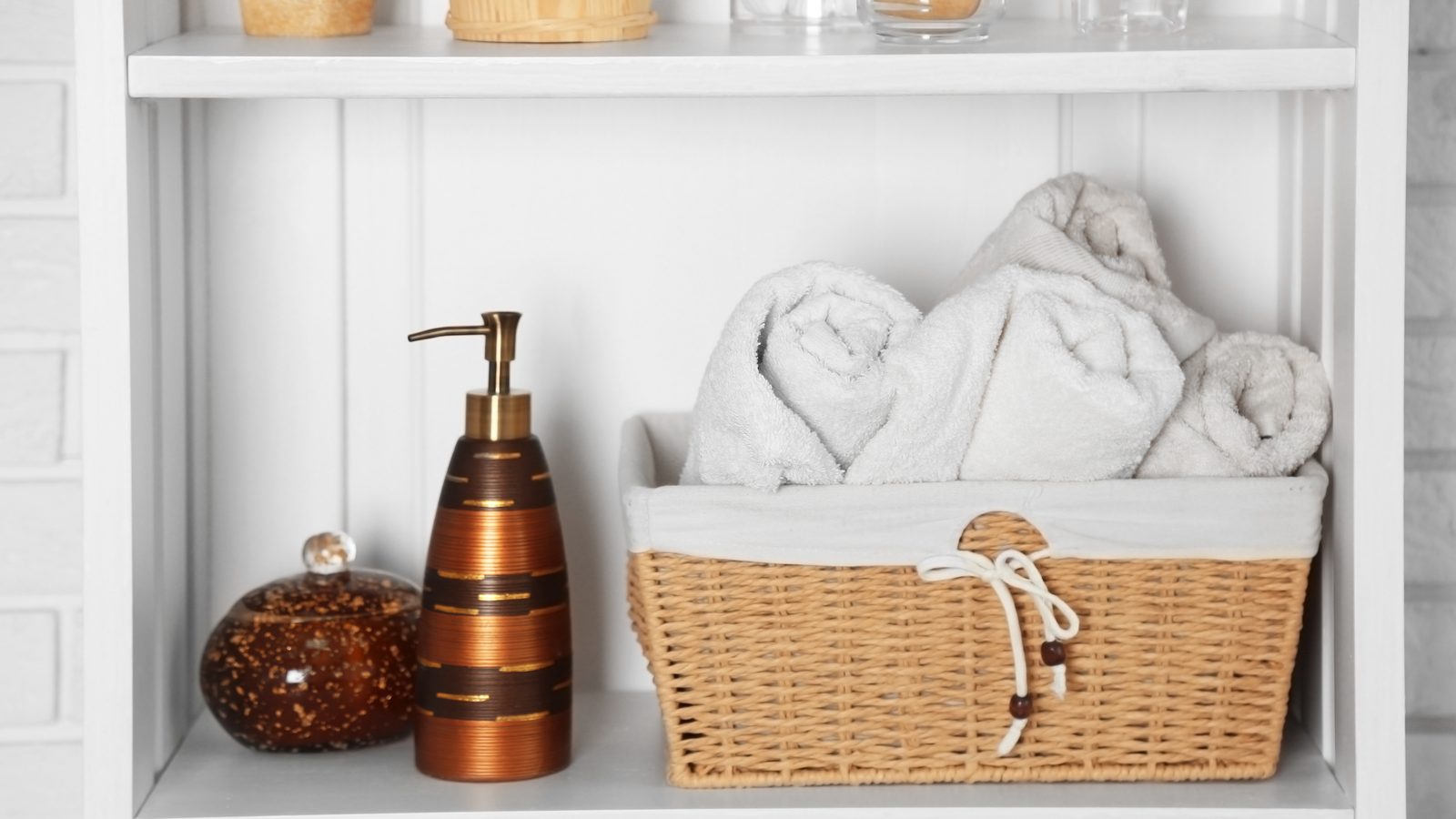Bathroom shelf with folded towels, a soap dispenser, and a woven storage basket
