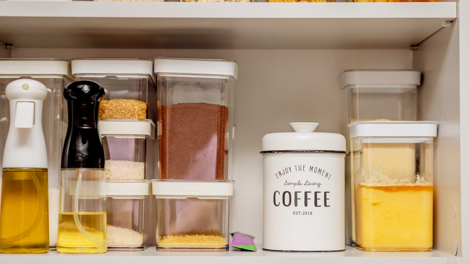 Organisateurs de rangement installés dans un placard de cuisine avec bocaux et produits bien classés