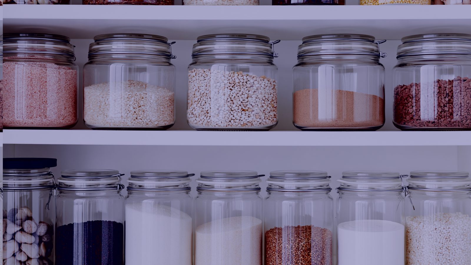 Organized pantry shelves lined with matching glass jars of grains and cereals