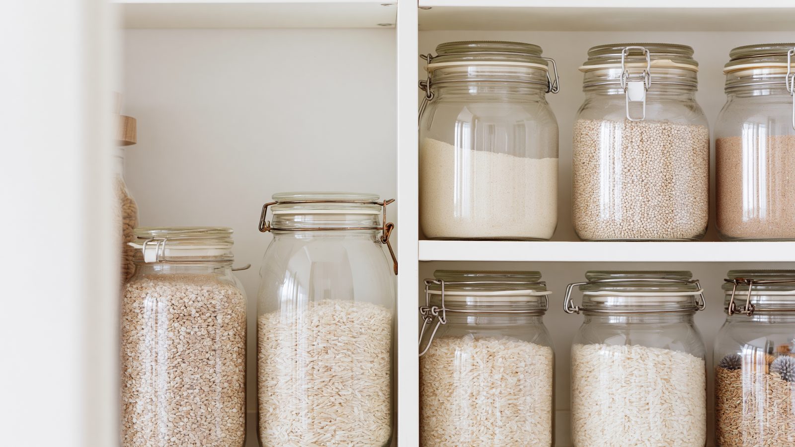 Glass jars and containers organizing dry goods on a pantry shelf