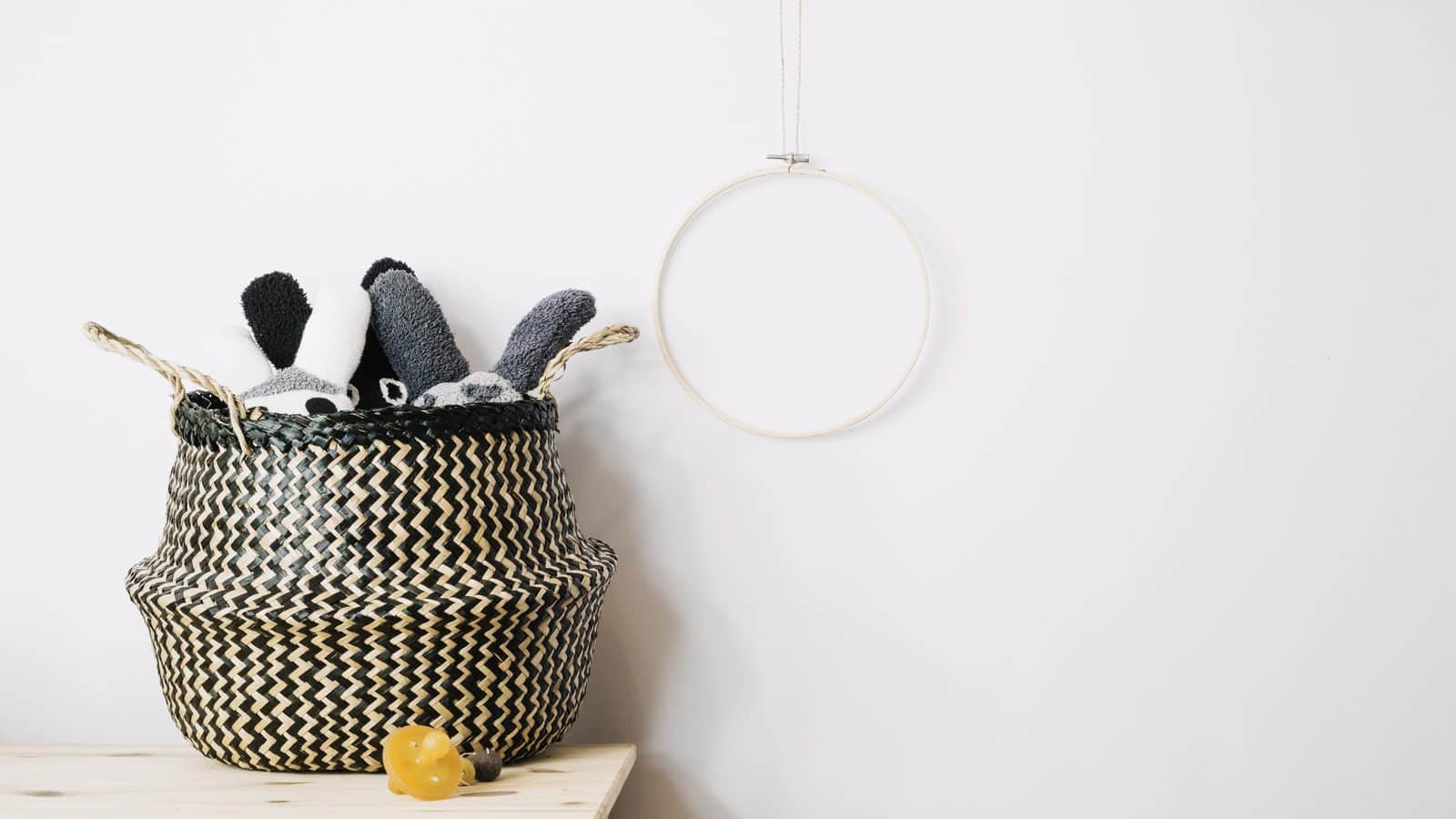 Closed woven basket holding toys on the bottom shelf of a living room bookcase