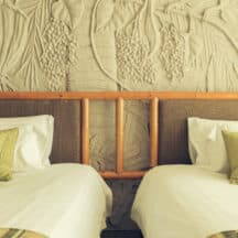 Deux lits simples identiques placés côte à côte dans une chambre partagée, literie blanche et grise assortie