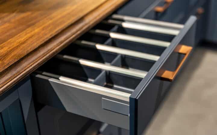 Tiroir de cuisine ouvert avec un organisateur vertical rangeant couvercles et ustensiles séparément